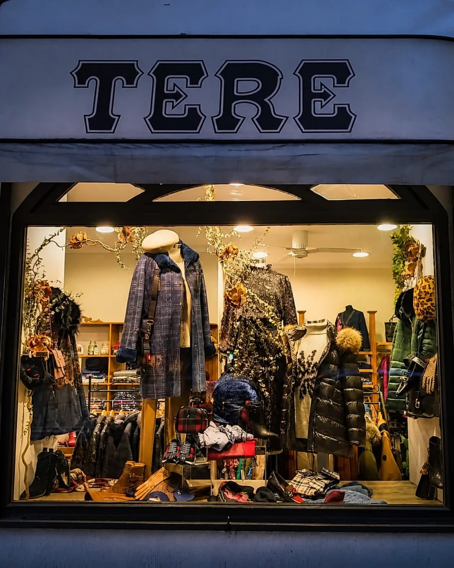 Fachada de la boutique Tere Moda en A Coruña al atardecer, con el rótulo TERE iluminado y el escaparate encendido.